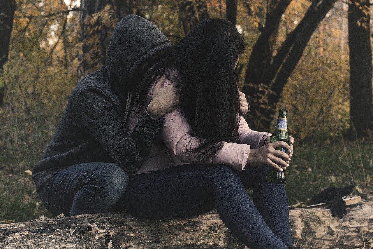 persona sosteniendo a una mujer que tiene una botella en la mano.